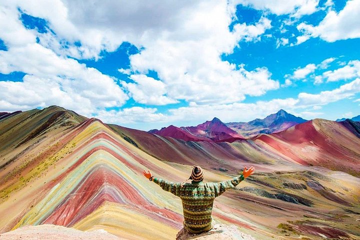 A hiker in front of the Rainbow Mountain stripes