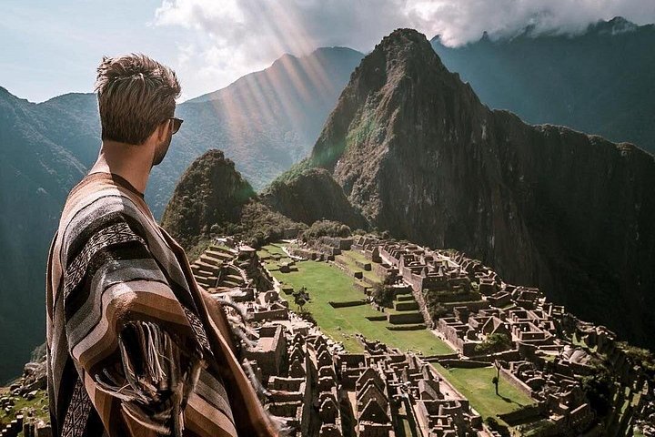 A visitor in a poncho looking over Machu Picchu